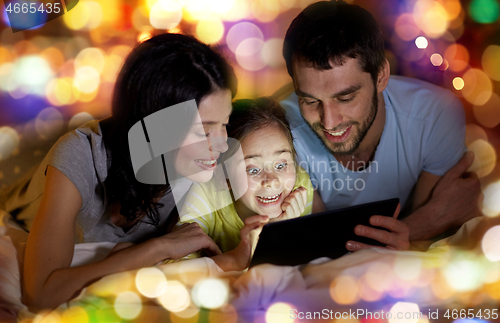 Image of family with tablet pc in bed at night at home