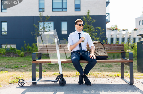 Image of businessman with scooter drinking smoothie in city