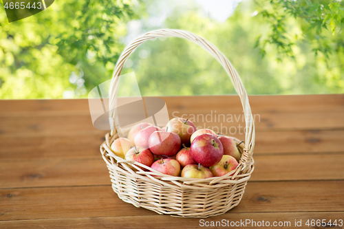 Image of ripe apples in wicker basket on wooden table