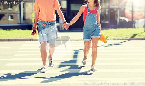 Image of teenage couple with skateboards on city crosswalk