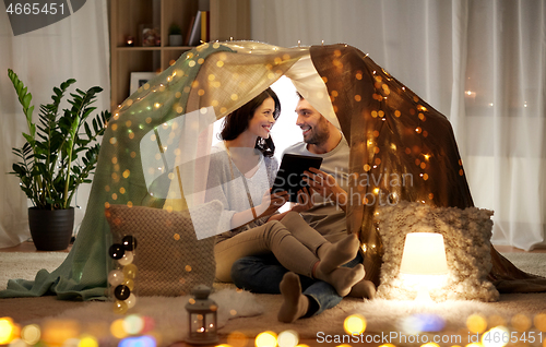 Image of happy couple with tablet pc in kids tent at home