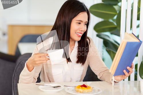 Image of woman drinking coffee and reading book at cafe