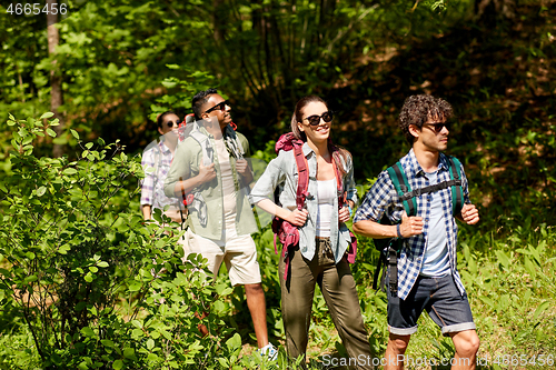 Image of group of friends with backpacks hiking in forest