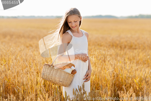 Image of girl with bread and milk in basket on cereal field