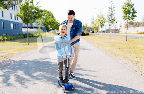 Image of happy father and little son riding scooter in city