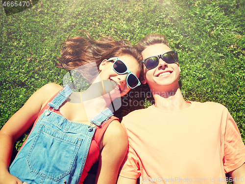 Image of happy teenage couple lying on grass at summer