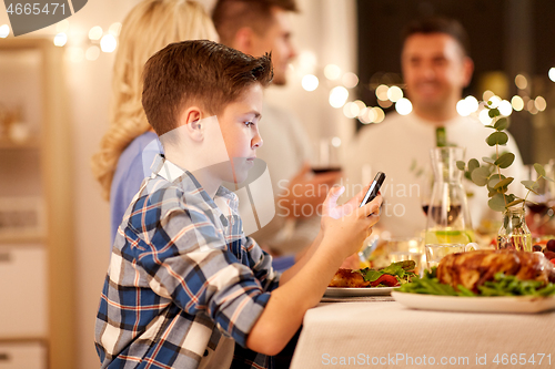 Image of boy with smartphone at family dinner party