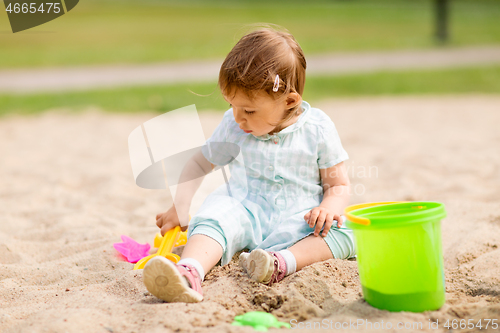 Image of little baby girl plays with toys in sandbox