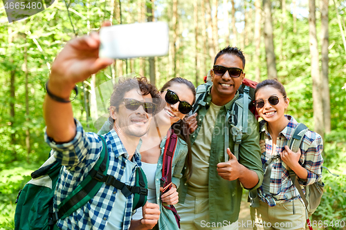 Image of friends with backpacks hiking and taking selfie