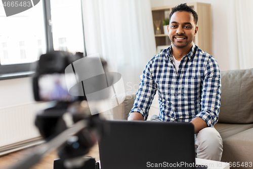 Image of male blogger with camera videoblogging at home