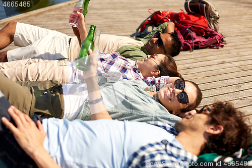 Image of friends drinking beer and cider on lake pier