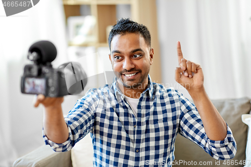 Image of male video blogger with camera blogging at home