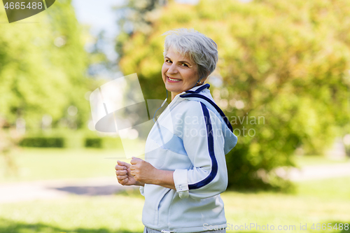 Image of senior woman with earphones running in summer park