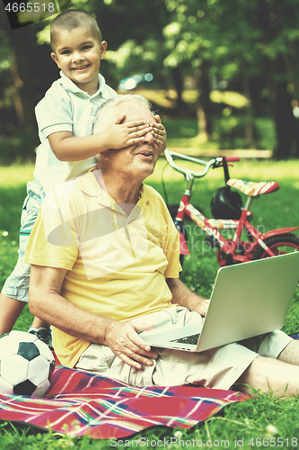 Image of grandfather and child using laptop