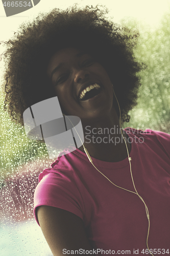 Image of portrait of young afro american woman in gym while listening mus