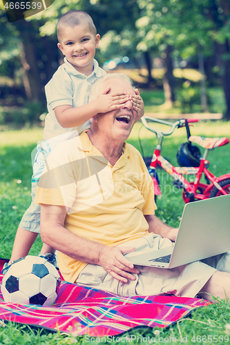 Image of grandfather and child using laptop