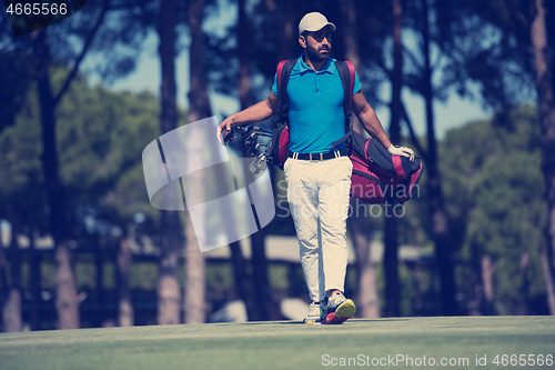 Image of golf player walking and carrying bag