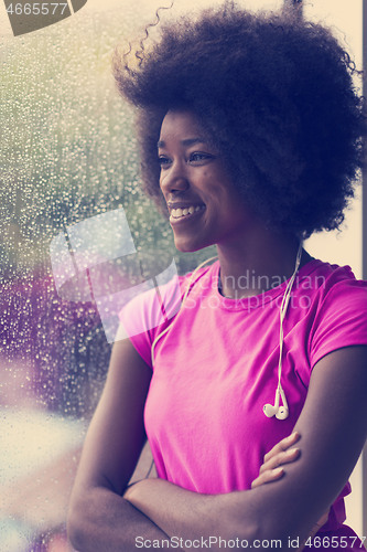 Image of portrait of young afro american woman in gym while listening mus