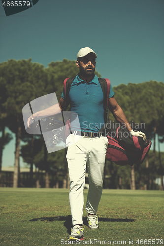 Image of golf player walking and carrying bag