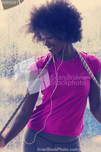 Image of portrait of young afro american woman in gym while listening mus