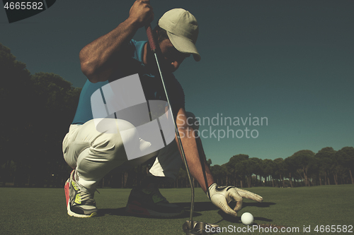 Image of man\'s hand putting golf ball in hole