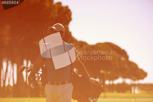 Image of golf player walking and carrying bag