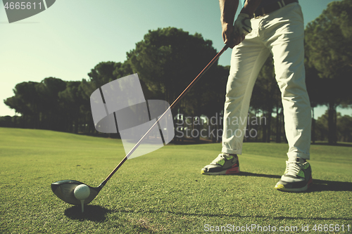 Image of golf player placing ball on tee