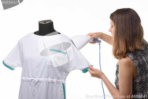 Image of Girl seamstress steals a medical gown before issuing to a client