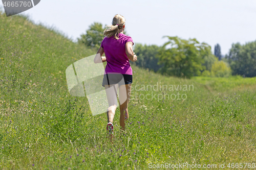Image of Young woman running in nature on a rural road 