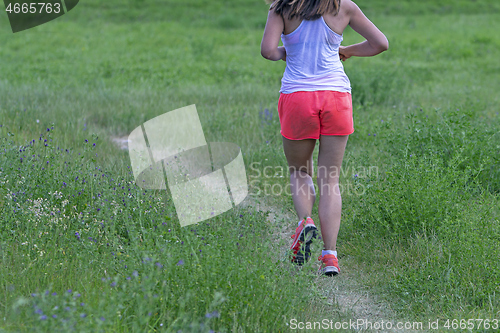 Image of Young woman running in nature on a rural road 