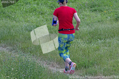 Image of Young woman running in nature on a rural road 