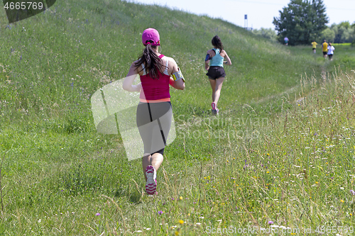 Image of Young women running in nature on a rural road 
