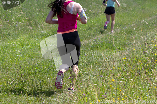 Image of Young women running in nature on a rural road 