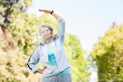 Image of happy senior woman exercising at summer park