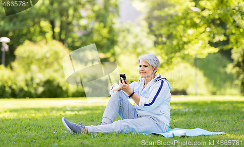 Image of sporty senior woman with earphones and smartphone