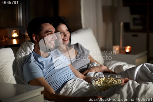 Image of couple with popcorn watching tv at night at home