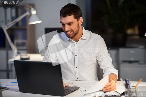 Image of businessman with laptop working at night office