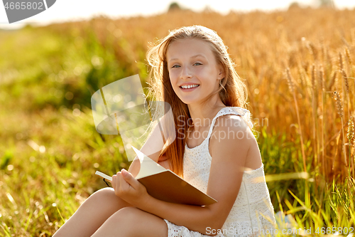 Image of smiling girl reading diary on cereal field