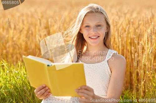 Image of smiling young girl reading book on cereal field