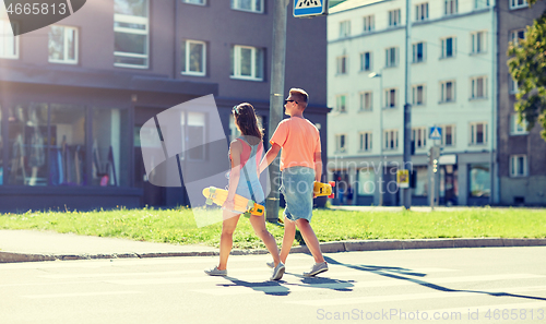 Image of teenage couple with skateboards on city crosswalk