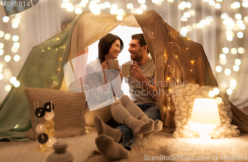 Image of couple drinking coffee or tea in kids tent at home