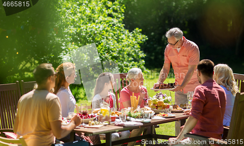 Image of happy family having dinner or summer garden party