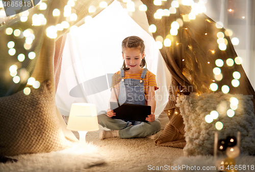 Image of little girl with tablet pc in kids tent at home