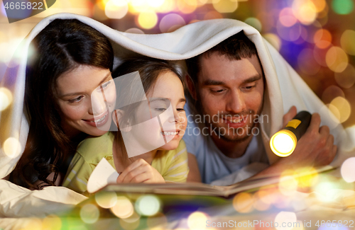 Image of happy family reading book in bed at night at home