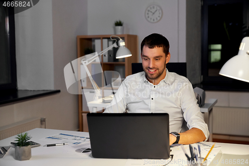 Image of businessman with laptop working at night office