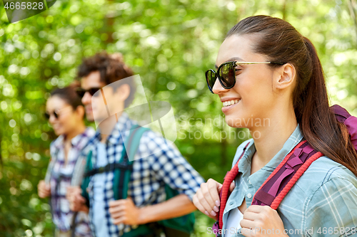 Image of group of friends with backpacks hiking in forest