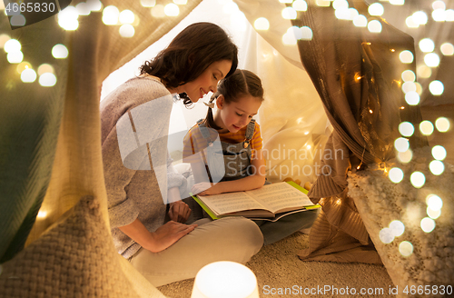 Image of happy family reading book in kids tent at home