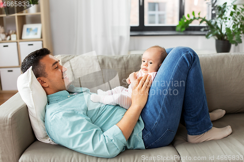 Image of middle aged father with baby lying on sofa at home