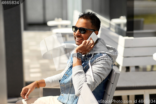 Image of indian man calling on smartphone at street cafe