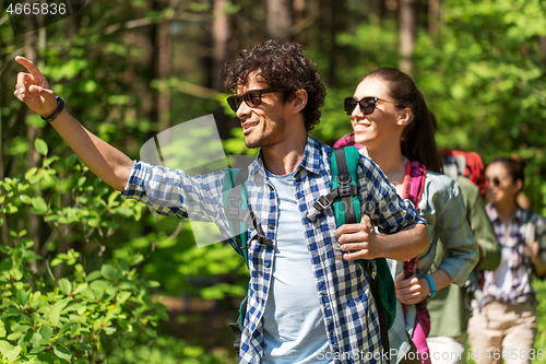 Image of group of friends with backpacks hiking in forest